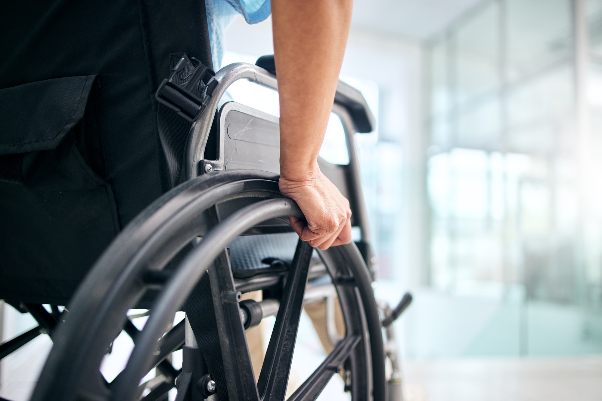 Hand, rehabilitation and person in a wheelchair at a hospital for medical support, transportation a